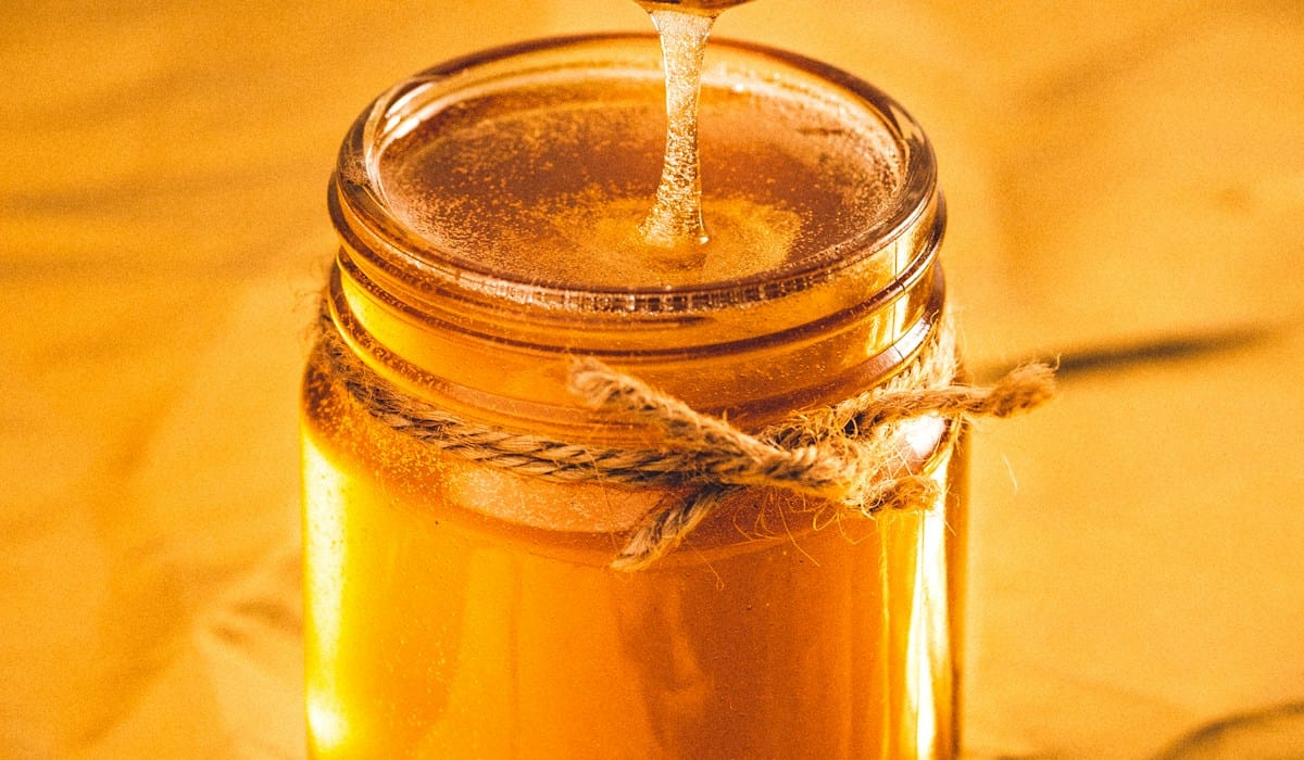 Authentic Manuka honey being poured with golden viscosity